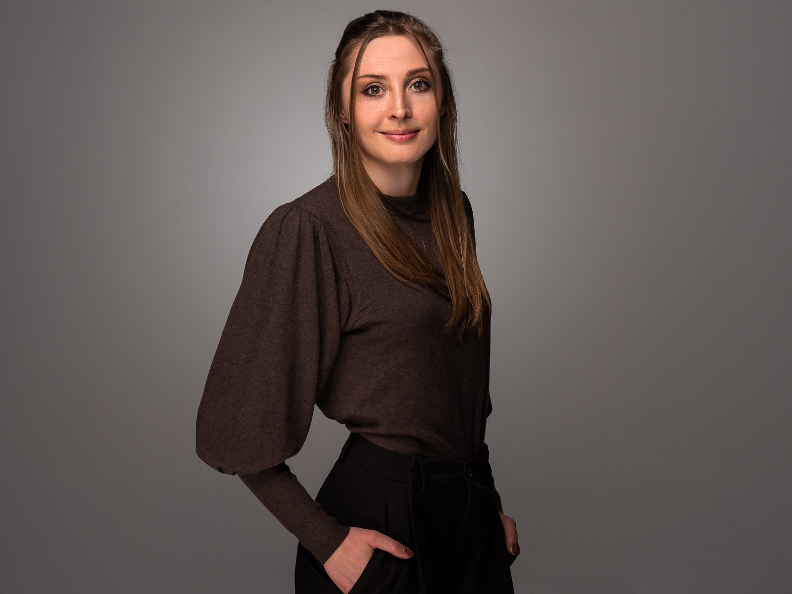 Bewerbungsfoto einer jungen Frau vor dunklem Hintergrund